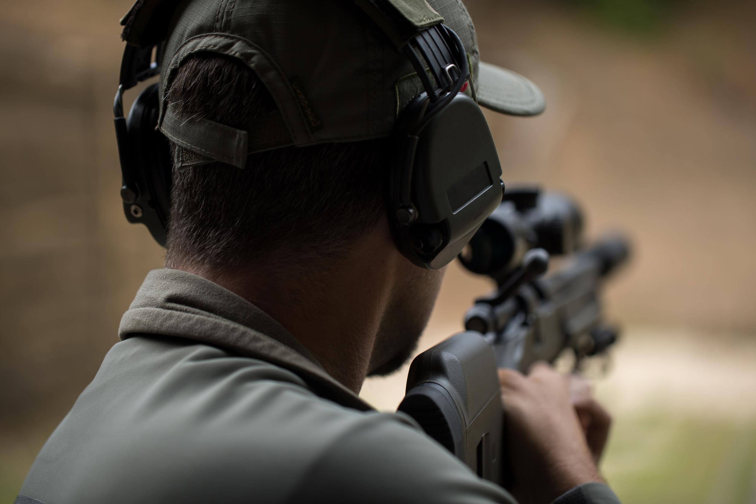 Sniper shooting rifle by looking through a scope.